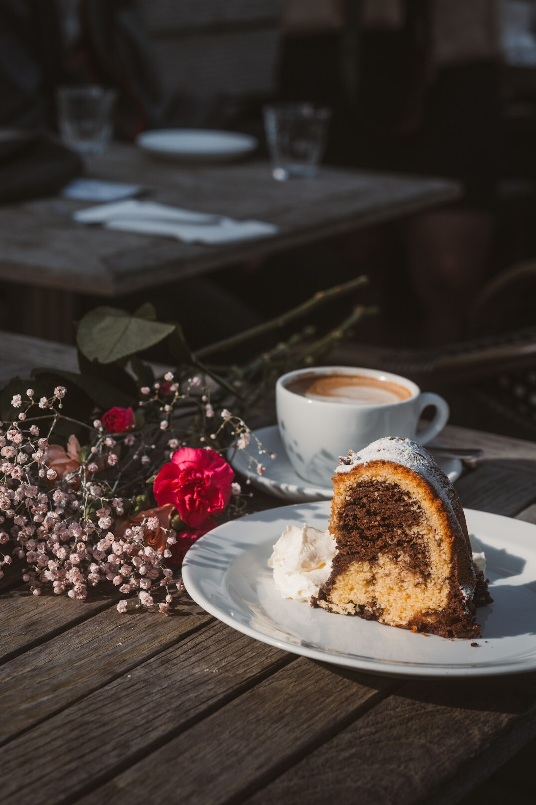 Cheerful older friends laughing together at a garden table with coffee and cake